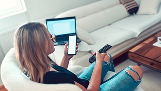 ragazza sul divano con telecomando e smartphone